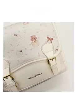 Detail of cute cat and cupcake prints on white leather handbag with gold buckles