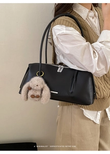 Detail der minimalistischen schwarzen Ledertasche mit silbernem Reißverschluss und Plüschhase