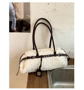 Detail of white plush faux fur tote with brown leather straps and silver metal buckle