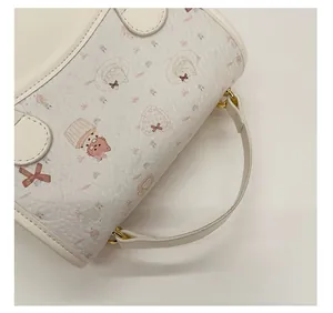 Detail of white faux leather bag showing cute cartoon prints and sturdy top handle