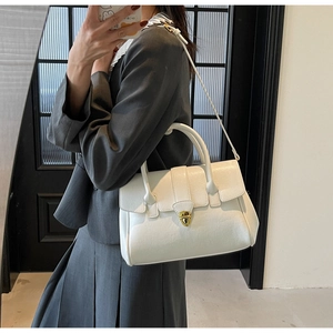 Detailed view of a white minimalist handbag with gold twist lock and smooth leather finish