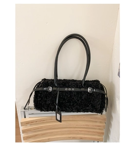 Detail of black faux shearling tote bag with smooth leather straps and silver buckle