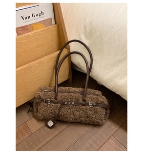 Detail of brown faux shearling tote bag with leather straps and silver metal buckles
