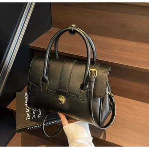 Detail of classic black leather briefcase with gold metal lock on rustic wooden steps
