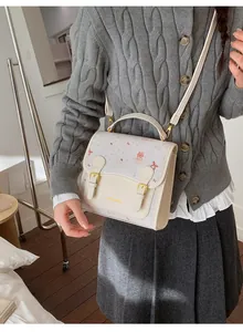 Detail of cute cartoon bear print on a cream white crossbody bag with metal buckles