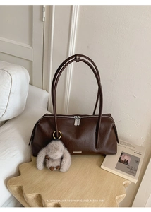 Detail der minimalistischen dunkelbraunen Ledertasche mit Silberlogo und Hasenanhänger