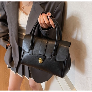 Detail of black leather handbag with elegant gold twist lock and sturdy top handles