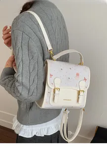 Close-up of a versatile cream cartoon bear backpack with gold hardware and logo detail