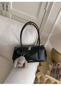 Detail der schwarzen Retro Leder Boston Bag mit Plüschhasenanhänger auf weißem Sofa