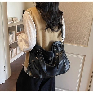 Detail of vintage black PU tote bag with metal grommets and gothic cross chain accessories