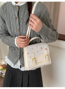 Detail shot of cute bear handbag featuring cartoon patterns and gold metal buckles