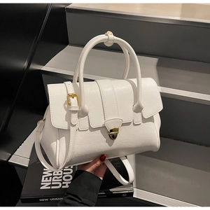 Close-up of white pebble leather handbag featuring a golden heart-shaped lock and strap