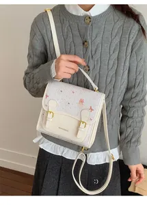 Detail of cream white cartoon satchel featuring pink prints and elegant bow decoration