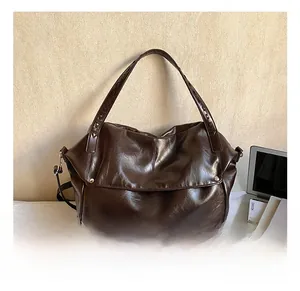 Detail of dark brown glossy leather tote bag with silver rivets and woven strap texture