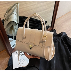 Detail view of cream leather handbag with golden twist lock and twin top handles