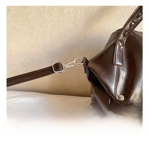 Detail showing the silver metal swivel hook and fine stitching on the dark brown bag strap