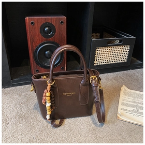Détail d'un sac à main vintage marron foncé avec charme en perles de bois et logo doré