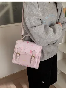 Detail view of pink cartoon handbag with golden buckles and cute character pattern