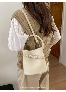 Détail du sac seau en cuir crème avec texture grainée et boucle métallique dorée