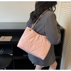 Detail of pink quilted tote bag featuring leather chain strap and glossy finish