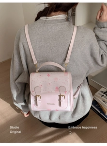 Detailed close-up of pink mini backpack with cute cat print and double buckle straps