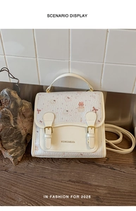 Detail of white leather handbag with cartoon bear print and golden metal buckles on wood