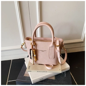 Détails d'un petit sac rose en similicuir avec breloque perlée et fermeture éclair