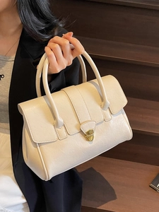 Elegant cream-white leather handbag with gold metal clasp shown on a fashion model
