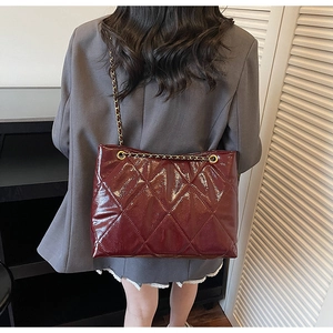 Détail du sac cabas bordeaux matelassé avec texture brillante et œillets en métal doré