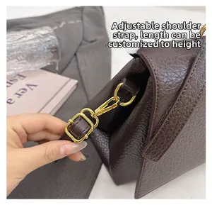 Détail de la bandoulière en cuir grainé marron foncé avec boucle en métal doré