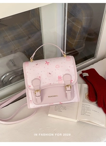 Close-up of pink bear handbag featuring cute cartoon cat prints and metal logo detail
