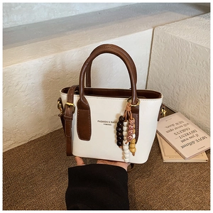 Detail of white and brown contrast tote bag with stylish wooden bead charm