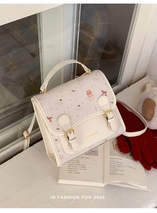 Close-up of cream cartoon bear handbag with gold buckles and pink bow details