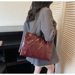 Mannequin portant un cabas bordeaux en cuir verni avec matelassage et chaîne dorée