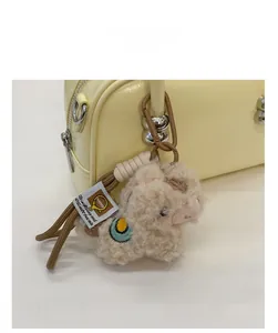 Détail du charm d'agneau en peluche avec broderie et fermoir sur un sac en cuir jaune