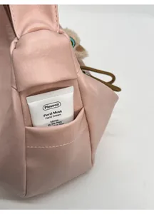 Detail view of pink leather dumpling bag side pocket with hand cream for size scale
