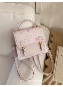 Detail of pink bear pattern backpack with bow straps and gold logo on white sofa