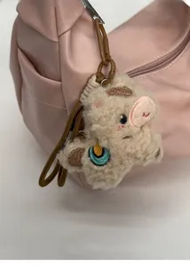 Detail of a cute alpaca plush keychain attached to a pink pleated dumpling bag