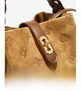 Close-up of geometric floral embroidery and golden twist lock on a vintage bucket bag