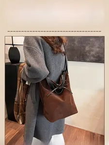 Close-up of a large brown suede bucket bag featuring elegant black leather bow detailing