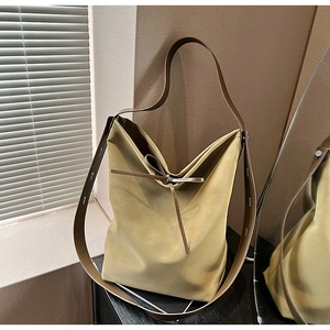 Detail of ginger yellow leather tote bag with brown adjustable strap and tie closure