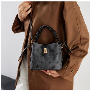 Detail of grey bucket bag with embossed floral pattern, woven handle and gold twist lock