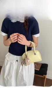 Détail du sac Boston en cuir jaune clair avec breloque mouton en peluche et anses