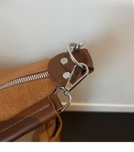 Close-up of silver metal hardware and rivets on brown lychee grain leather bag detail