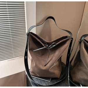Detail of dark brown hobo tote with black bow tie and adjustable wide strap