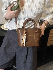 Sac à main en cuir marron brillant avec pompon en perles de bois et lettrage doré chic