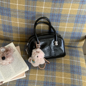 Détail du sac polochon en cuir brillant noir avec finitions argentées et charm en peluche