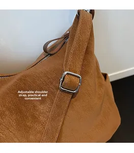 Close-up of adjustable silver metal buckle on brown lychee texture leather tote bag