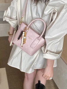 Pink faux leather bucket bag for women with crossbody strap and beaded charm accessory