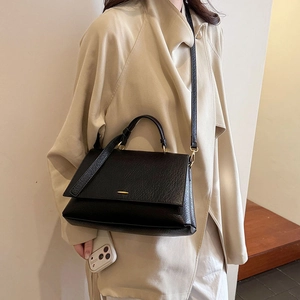 Gros plan du sac cabas en cuir noir minimaliste avec texture litchi et boucle dorée